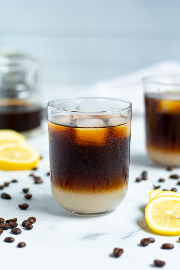 Splash of iced coffee in tall glass and coffee beans. Stock Photo