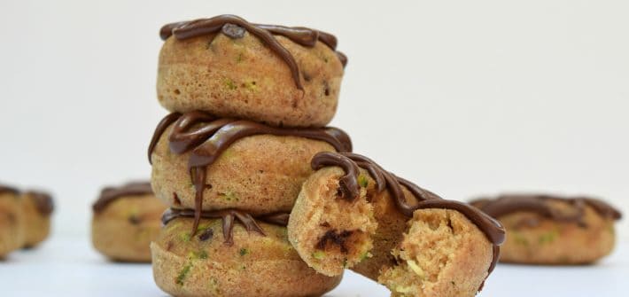 stack of 3 baked zucchini donuts and a 4th donut with a bite taken out of it