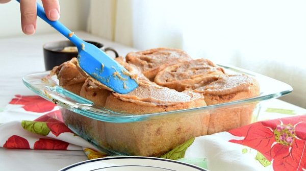 spatula spreading date caramel onto yeast whole wheat rolls