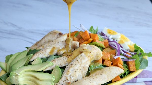 Honey Mustard Dressing being poured onto the salad