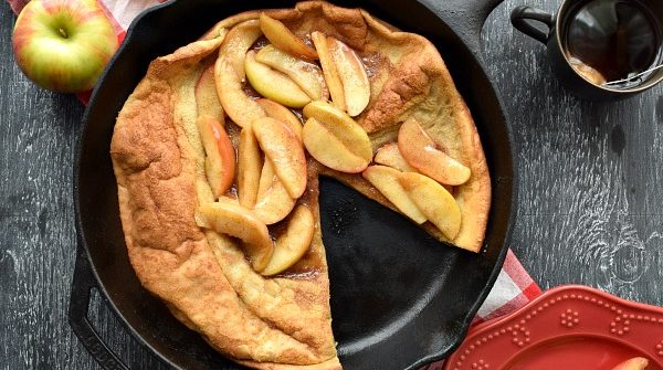 Overhead Cinnamon Apple Topped Dutch Baby with a slice cut out