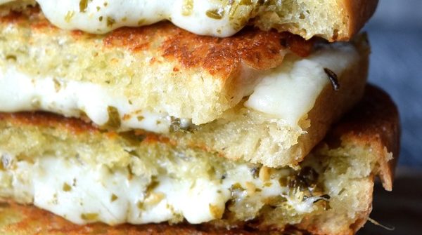 Pesto Grilled Cheese stacked up with melting cheese and pesto