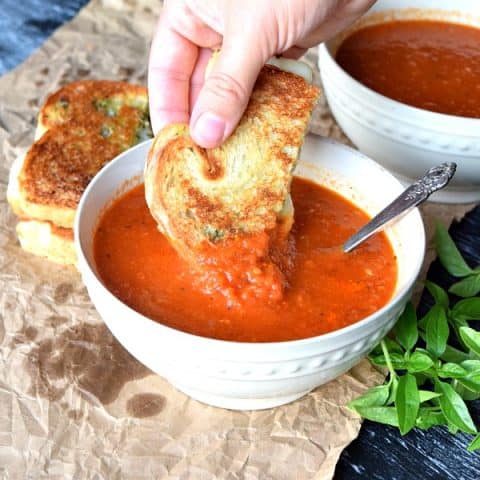 Roasted Red Pepper & Tomato Soup with a grilled cheese being dipped in