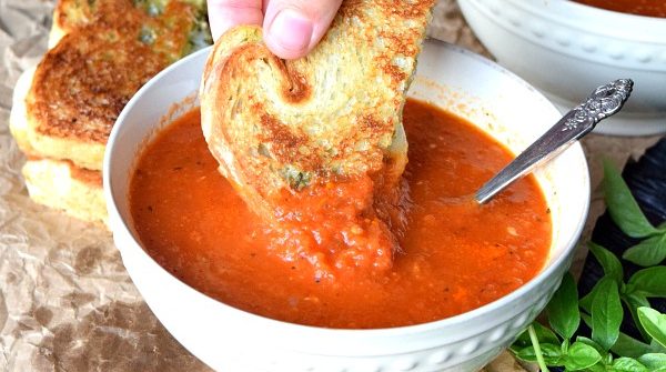 Roasted Red Pepper & Tomato Soup with a grilled cheese being dipped in