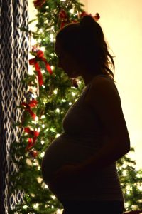 pregnancy bump silhouette in front of christmas tree