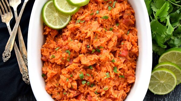 overhead shot of mexican rice with limes, cilantro, and forks