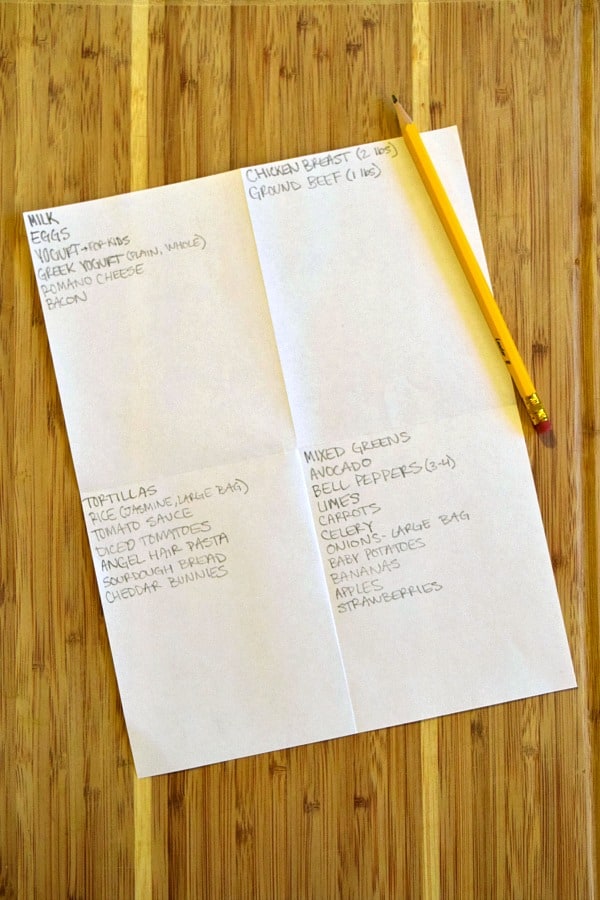 a grocery list divided into 4 sections with a pencil