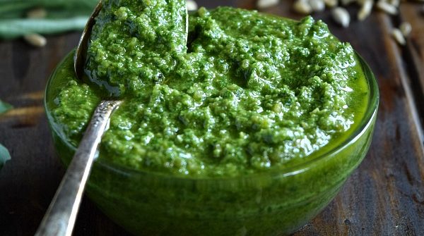 Sunflower Seed Basil Pesto in a small bowl with a spoonful ready to be spread and tossed with your next meal