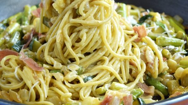 Summer Spaghetti Carbonara being pulled out of a large skillet showing the pasta covered in creamy carbonara sauce