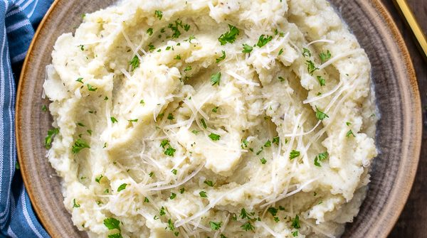 bowl of garlic parmesan mashed cauliflower on a wood table