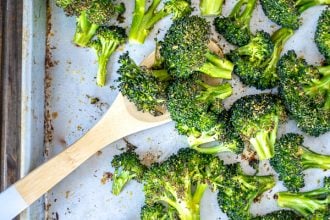 A wooden spoon scooping up oven roasted broccoli