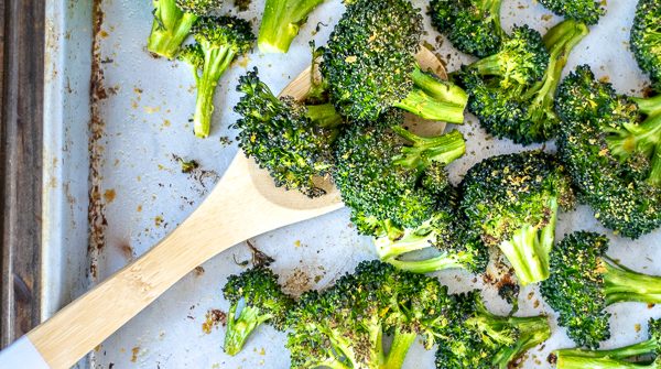 A wooden spoon scooping up oven roasted broccoli