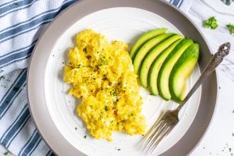 cottage cheese scrambled eggs and sliced avocado on a plate with a fork