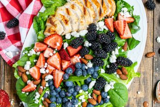 overhead view of a summer berry salad on a large platter with a napkin and a lot of berries