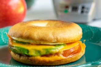 avocado breakfast sandwich sitting on a teal plate