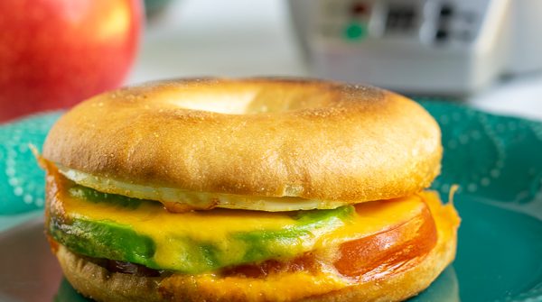 avocado breakfast sandwich sitting on a teal plate