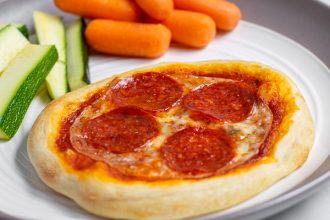close up of individual pizza on a plate with vegetables perfect for a weeknight dinner