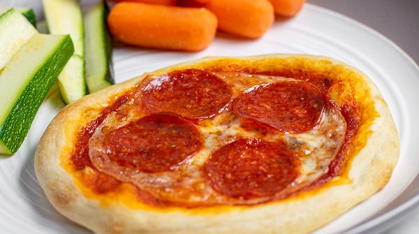 close up of individual pizza on a plate with vegetables perfect for a weeknight dinner
