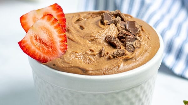 healthy best chocolate hummus in a white bowl sprinkled with chocolate shavings and slices of strawberries