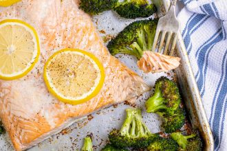 forkful of baked salon with broccoli on a sheet pan