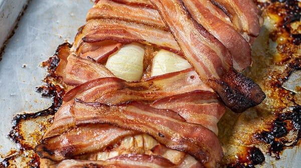 bacon wrapped meatloaf mummy on a sheet pan perfect for halloween dinner