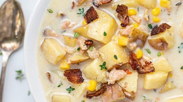 Healthy Clam Chowder in a white bowl with a spoon and oyster crackers