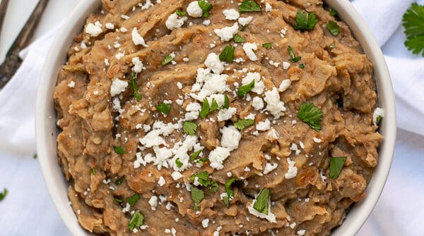 recipe for refried beans made in the instant pot in a white bowl with cilantro
