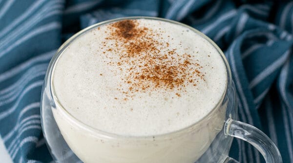 milk steamer drink in a clear mug with cinnamon sprinkled on top