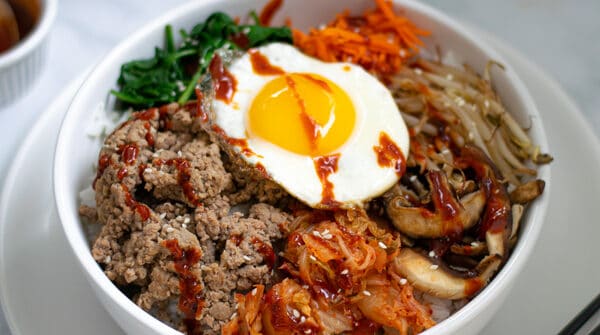 korean bibimbap bowl sitting on a table with chopsticks and kimchi