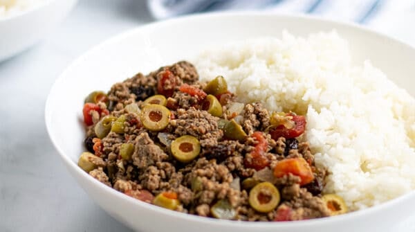 bowl of Cuban Picadillo with white rice on a table with forks
