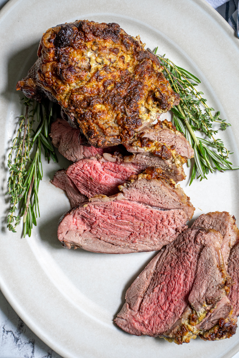 Overhead close up of a half sliced up roasted leg of lamb show tender pink meat.