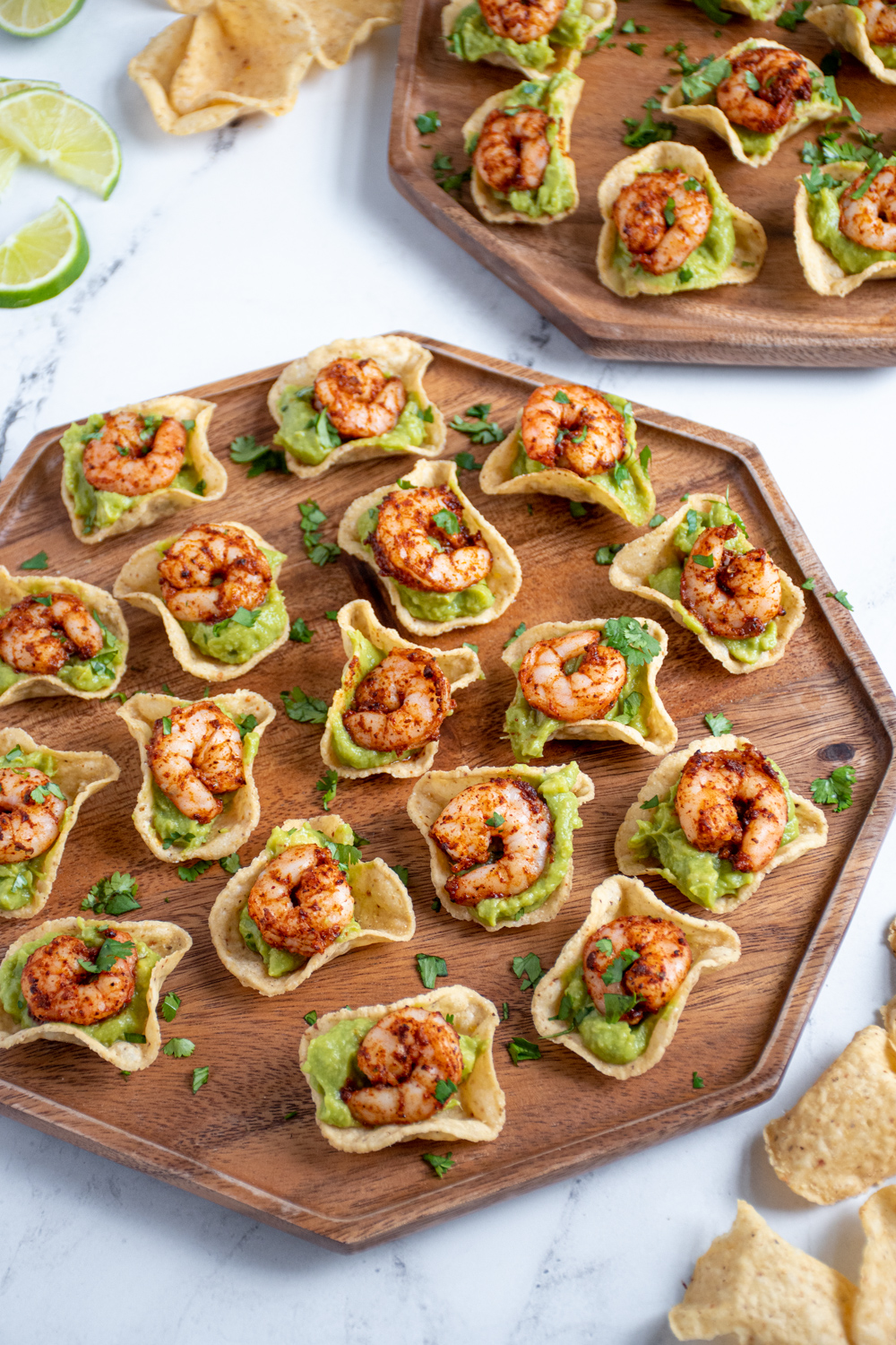 A wood platter filled with shrimp guacamole bites garnished with fresh cilantro.