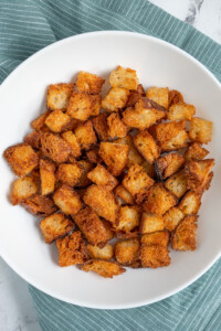 A white bowl filled with crunchy golden brown Air Fryer Croutons.