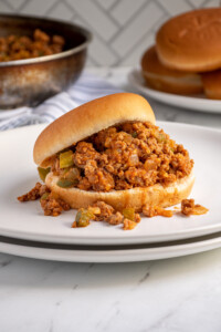 A bun filled with ground turkey sloppy joes on a plate.