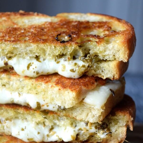 Pesto Grilled Cheese stacked up with melting cheese and pesto