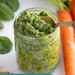 Pinterest pin with text overlay "Carrot Top Pesto", image of a glass jar with green carrot top pesto.