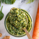 Pinterest pin with text overlay "Carrot Top Pesto", image of a glass jar with green carrot top pesto.