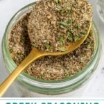 Pinterest Pin with text overlay "Greek Seasoning Recipe", image of a jar with a resting spoon full of greek seasoning.