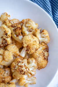 Freshly made air fryer cauliflower in a white bowl showing off the seasoned and crispy cauliflower.