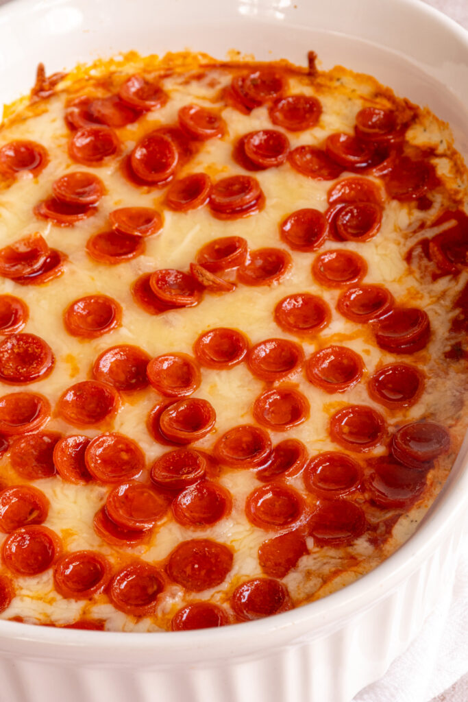 An angle view of a casserole dish with cottage cheese pizza dip topped with mini pepperoni.