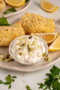 A small bowl with tartar sauce made with greek yogurt garnished with chopped pickles.