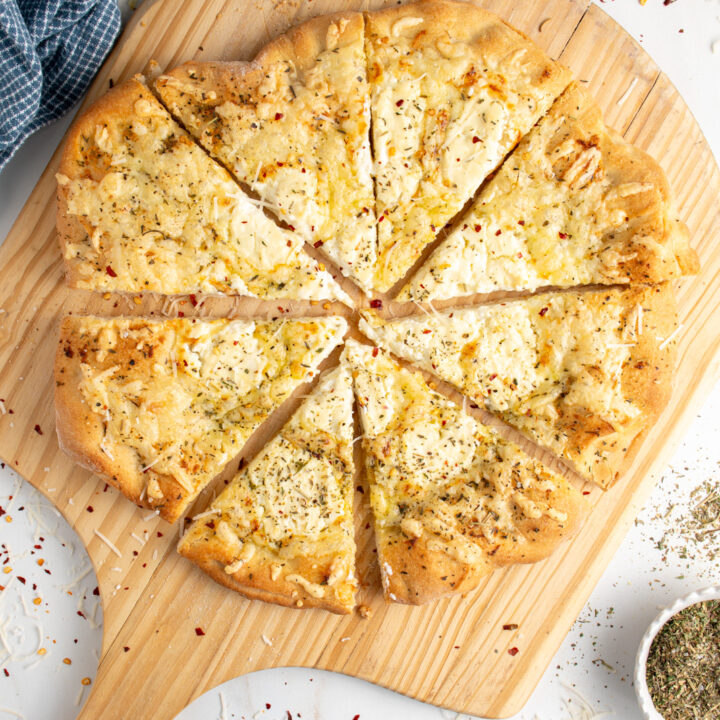 A sliced white pizza on a wood pizza peel.