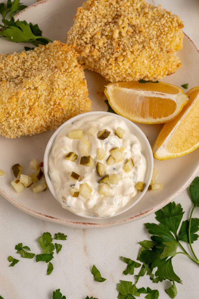 A small bowl with tartar sauce made with greek yogurt garnished with chopped pickles.