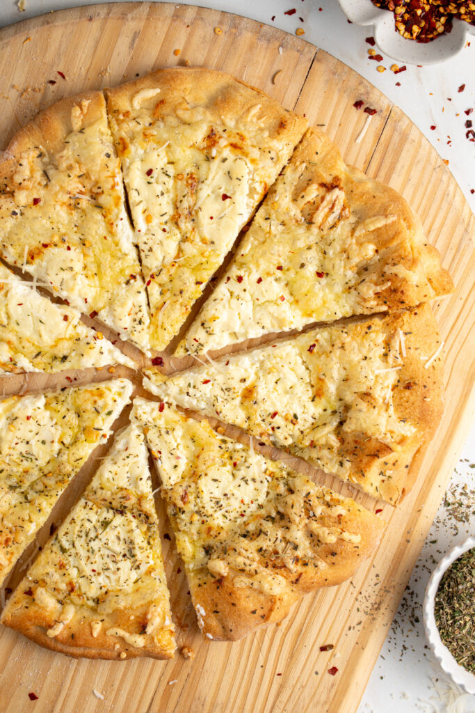 A sliced white pizza on a wood background.