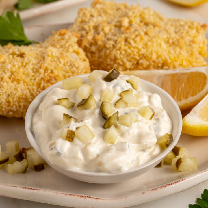 A small bowl with tartar sauce made with greek yogurt garnished with chopped pickles.