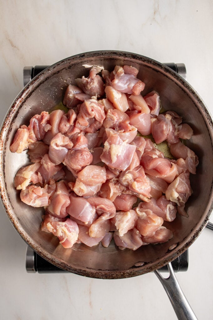 Raw chicken in a skillet.