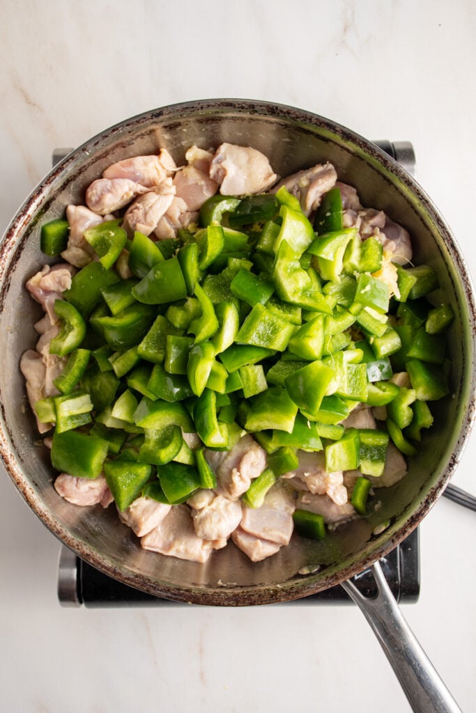 Adding green pepper to a skillet.