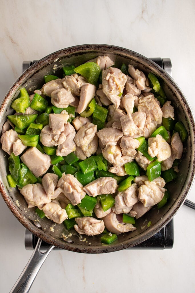 Cooking a chicken and bell pepper in a skillet.