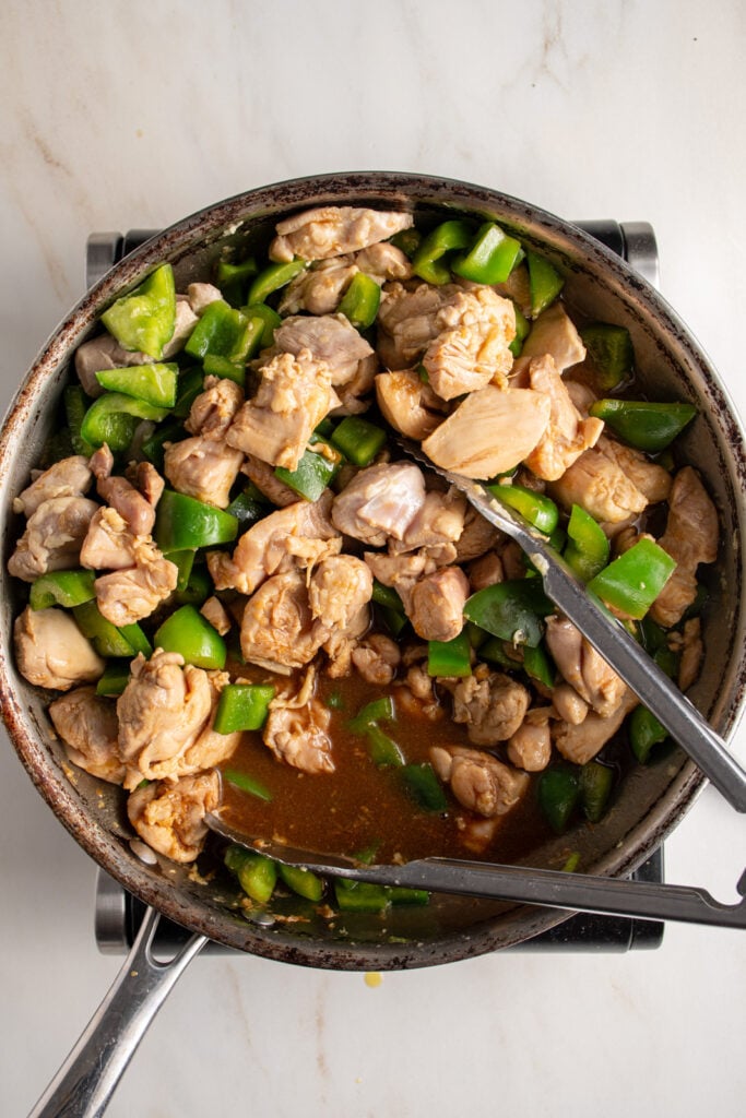 Cooking the sauce in the stir fry with chicken and bell pepper.