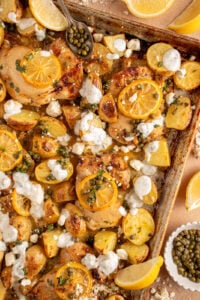 A sheet pan with balsamic chicken thighs, lemon, potatoes, and tzatziki.